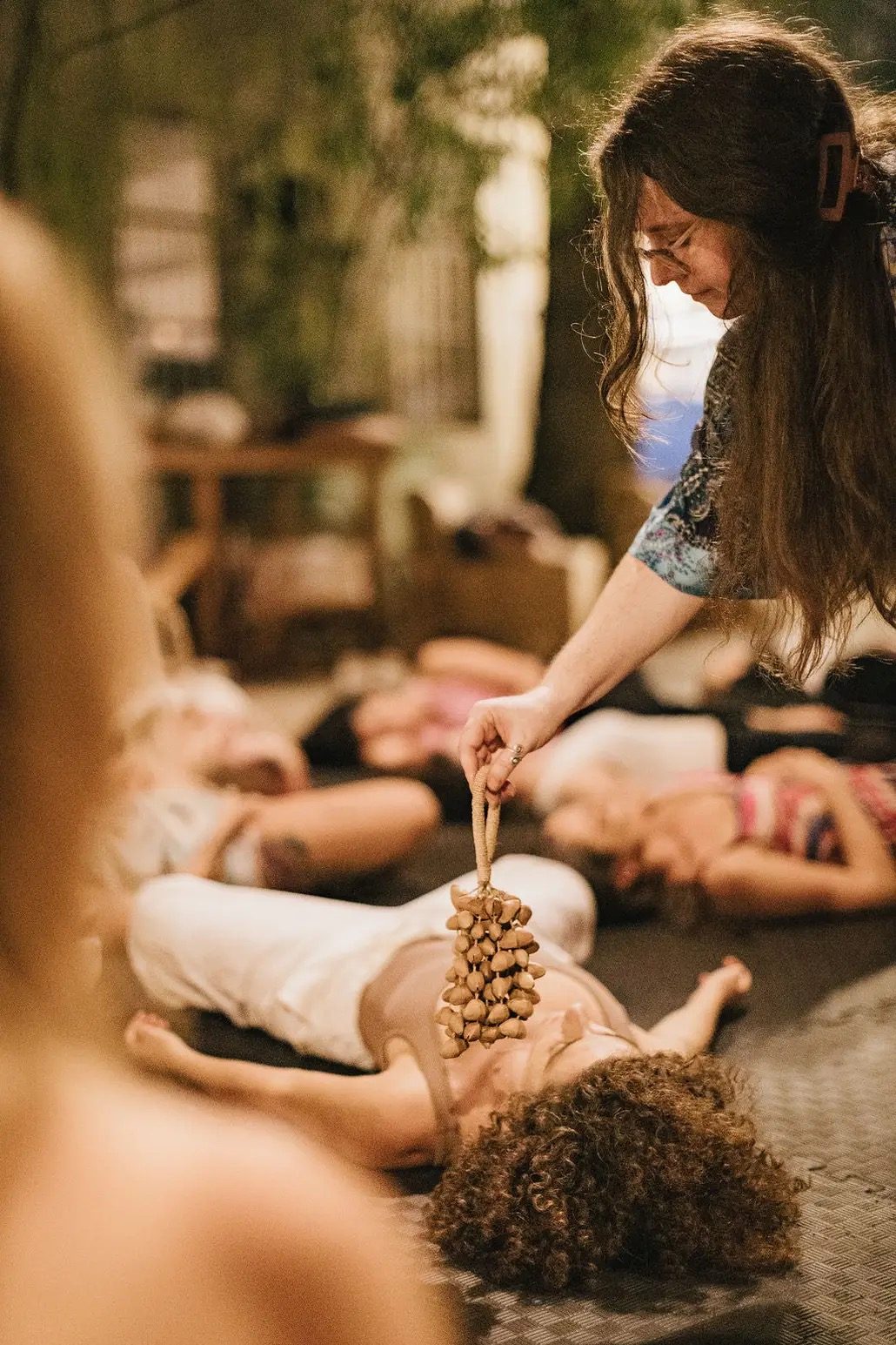 Ashley placing a seed-pod rattle over a participant during a session